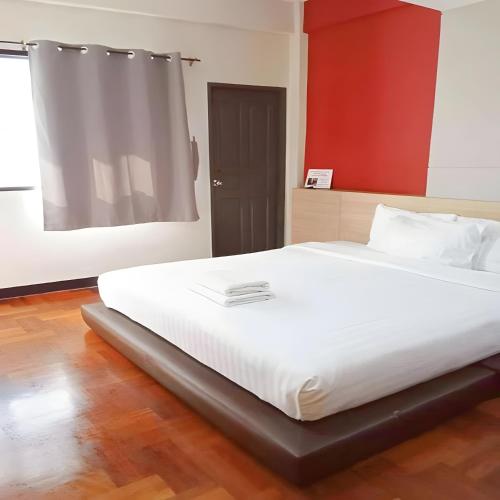 a large white bed in a room with a red wall at XX GO INN Silom BTS Saint Loius - เซนหลุย in Yan Nawa