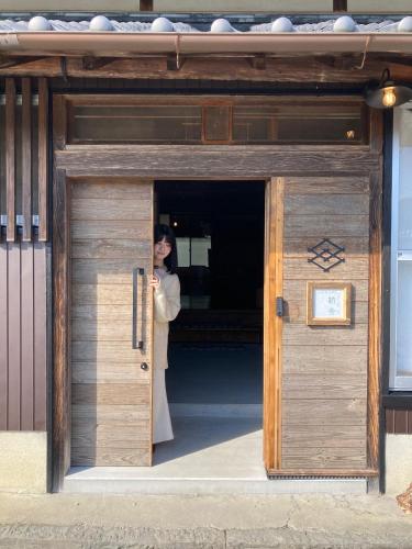 a woman standing inside of a wooden door at HANARE紡舎Tsumugiya in Ogawa