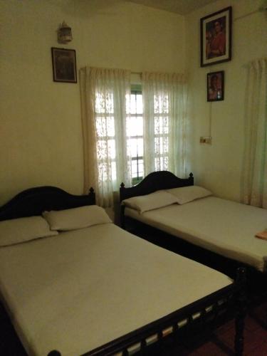 two beds sitting in a room with a window at Green Woods Bethlehem in Cochin