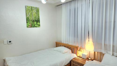 ein Schlafzimmer mit zwei Betten und einem Fenster in der Unterkunft Sim stay심스테이-매일 침구세탁clean bed in Mŏnnae