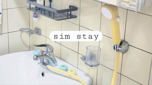 ein Waschbecken im Badezimmer mit Thermometer und Spiegel in der Unterkunft Sim stay심스테이-매일 침구세탁clean bed in Mŏnnae