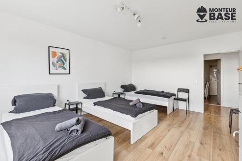 Habitación con 2 camas, paredes blancas y suelo de madera. en MONTEUR - Unterkunft für bis zu 6 Personen in 63454 Hanau - HU11, en Hanau am Main
