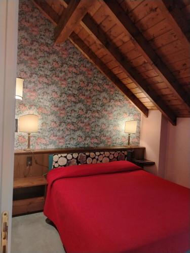 a bedroom with a red bed with a red blanket at Hotel Ristorante La Lepre Bianca in Gallio