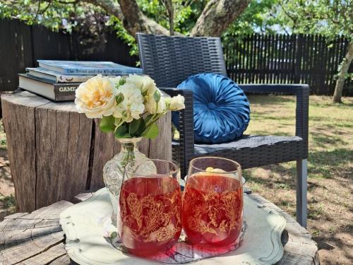 een tafel met twee glazen en een vaas met bloemen bij Cinnamon & Sage Country Cabins in Dullstroom
