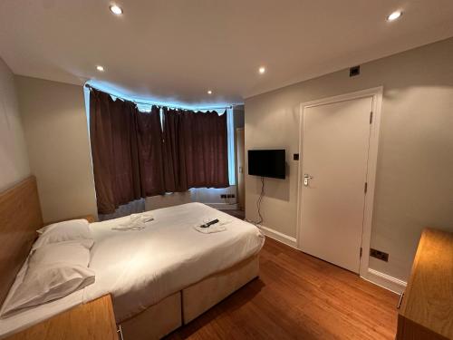 ハイ・ウィカムにあるCavendish Hotelの大きな白いベッドとテレビのある寝室