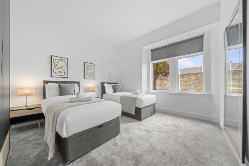 a white bedroom with two beds and a window at Harbour Hideaway in Fife