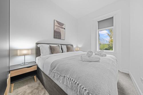 a white bedroom with a large bed and a window at Spacious 2 Bed Apartment - Perfect for Long or Short Stays - Sleeps 4 - Free On Street Parking in Fife