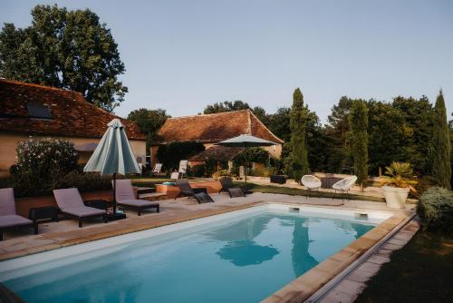 a swimming pool with chairs and an umbrella next to a house at Lodge Les Étoiles in Saint-Sauveur