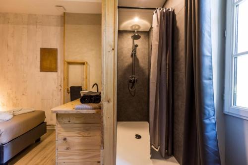 a bathroom with a shower and a sink and a bed at Au p'tit tcheste in Hontanx