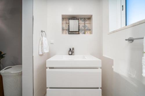a white bathroom with a sink and a mirror at Orange Blossom Grove in Cerro das Taipas