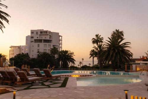 une piscine avec des chaises longues et un bâtiment dans l'établissement President Hotel, au Cap