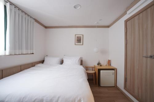 a bedroom with a white bed and a wooden door at stay105행궁 in Suwon