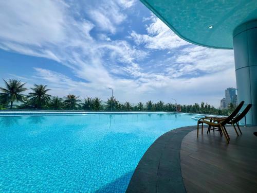 ダナンにあるNesta Celia Da Nang Hotelの建物の隣に椅子2脚付きのスイミングプール