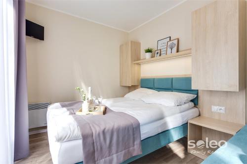 a bedroom with a white bed with a blue headboard at SOLEO Family Resort - domki 3 min od Morza - 3 Baseny, 3 Jacuzzi, Sauna, ANIMACJE, Małpi Gaj, 3 Sale Zabaw, 4 Place Zabaw, 2 Restauracje in Rewal