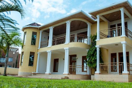 a large yellow house with a balcony at Elegant Villa Apart in Kigali