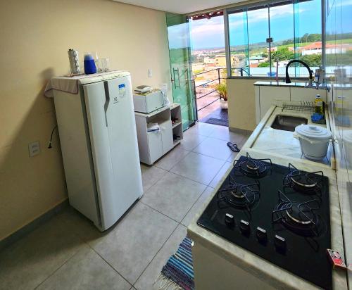 a kitchen with a stove and a refrigerator at Kitnet Aconchego in São João del Rei