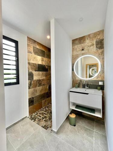 a bathroom with a sink and a mirror at Villa Aloha - classée 5 étoiles - avec piscine in Les Trois-Îlets