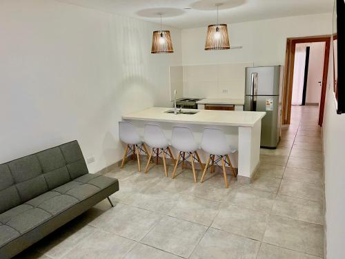 eine Küche mit Couch und Kücheninsel mit Hockern in der Unterkunft Departamentos a estrenar, zona parque in Necochea