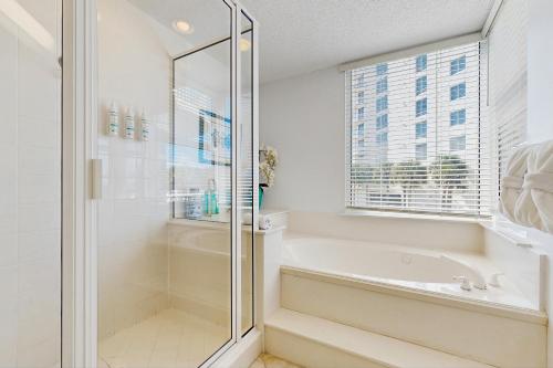 ein weißes Bad mit einer Dusche und einer Badewanne in der Unterkunft Beach Colony Resort West 1E in Navarre