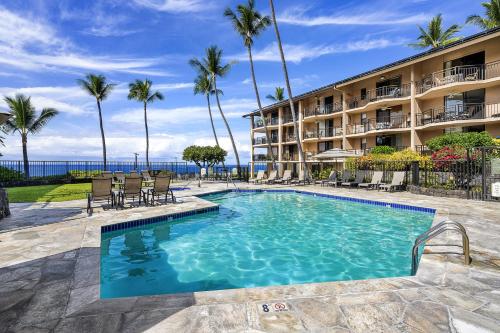 una piscina di fronte a un hotel con palme di Kona Makai 2103 a Kailua-Kona