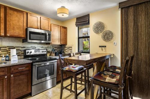 a kitchen with wooden cabinets and a table with a stove at Kona Makai 2103 in Kailua-Kona