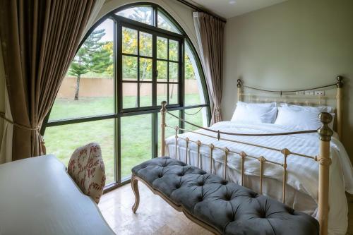 une chambre avec un lit et une grande fenêtre dans l'établissement My Ozone Villa Khaoyai มายโอโซน วิลล่า เขาใหญ่, à Ban Sap Setthi