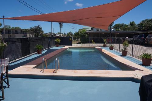 a swimming pool with a red umbrella over it at A & A Motel in Proserpine
