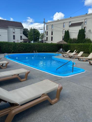 a swimming pool with chaise lounge chairs and a swimming pool at Au p'tit cocon sur le lac in Magog-Orford