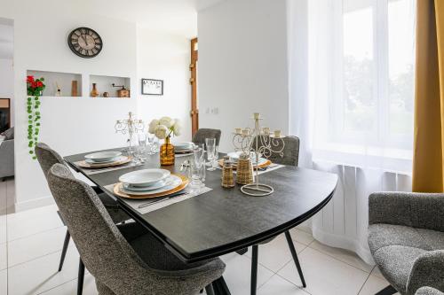 a dining room with a black table and chairs at La Rochoise - Parking, Wifi, proche Fontainebleau in La Grande-Paroisse