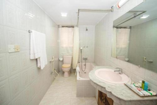a white bathroom with a sink and a toilet at Suite Palace in Dhaka