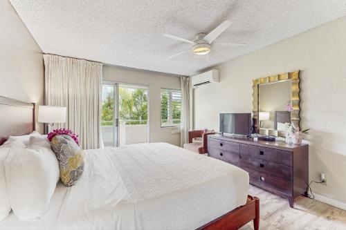 a bedroom with a bed and a dresser with a mirror at Plantation Hale D10 in Kapaa