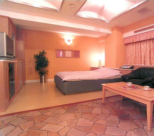 岡山市にあるHotel Queen's Court -ホテル クインズコート-のベッドとリビングルームのある寝室