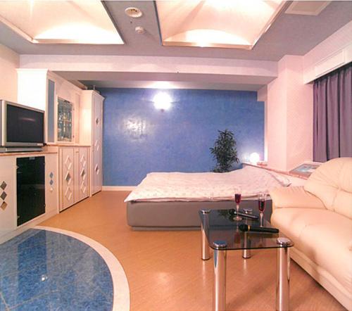 岡山市にあるHotel Queen's Court -ホテル クインズコート-のベッドとソファのあるリビングルーム