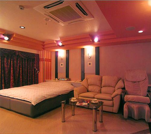 a bedroom with a bed and a couch and a table at Hotel Queen's Court -ホテル クインズコート- in Okayama