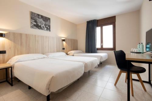 a hotel room with three beds and a desk at Hotel Encamp by Nexta in Encamp