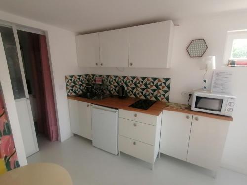 a kitchen with white cabinets and a microwave at L'Escale studio - Terrasse - Parking gratuit in Montpellier