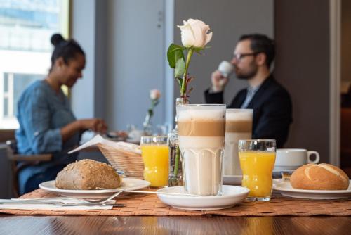 a table topped with glasses of orange juice and bread at acom Hotel Berlin Kurfürstendamm in Berlin
