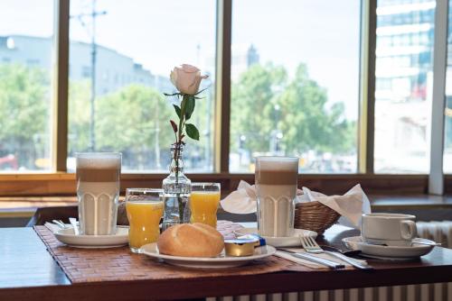 a table with a rose and a plate of food and drinks at acom Hotel Berlin Kurfürstendamm in Berlin