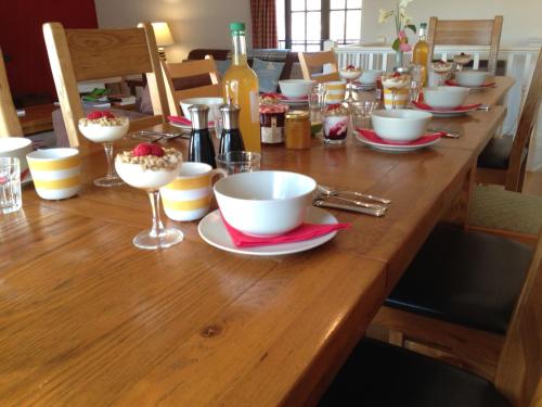 un tavolo di legno con ciotole e tazze sopra di Lower Marsh Farm B&B a Saltash