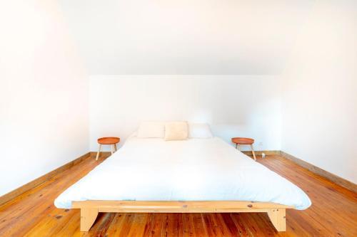 a bed in a room with white walls and wooden floors at Ce Petit Penty in Douarnenez