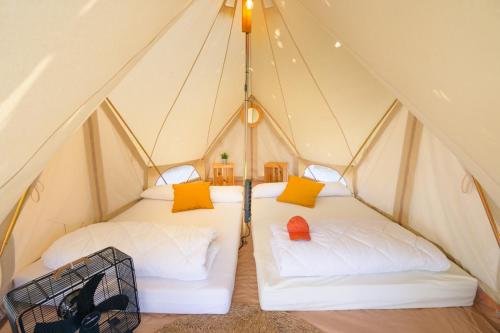 dos camas en una tienda de campaña con almohadas amarillas y naranjas en O Pedrouzo Base Camp, en O Pino 