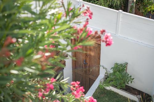a wooden door in a white fence with pink flowers at La Kazaka Terre Sainte in Saint-Pierre