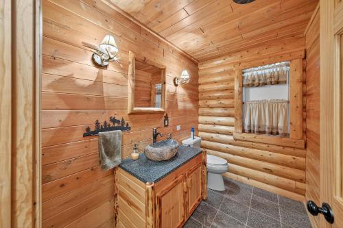 a log cabin bathroom with a sink and a toilet at Forest Glade in Sturgis