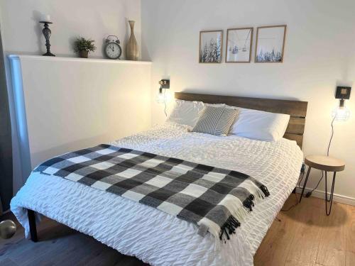 a bedroom with a bed with a black and white blanket at Ski in out au pied des pentes in Bromont