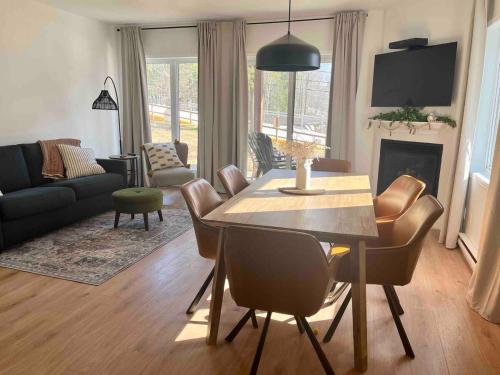 a living room with a dining table and a living room with a couch at Ski in out au pied des pentes in Bromont
