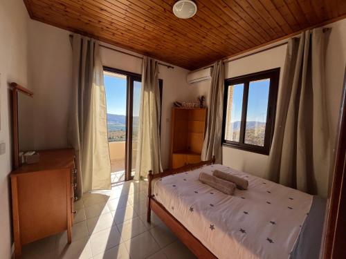 a bedroom with a bed and large windows at House on a Hill with Stunning Views near Troodos in Silikou