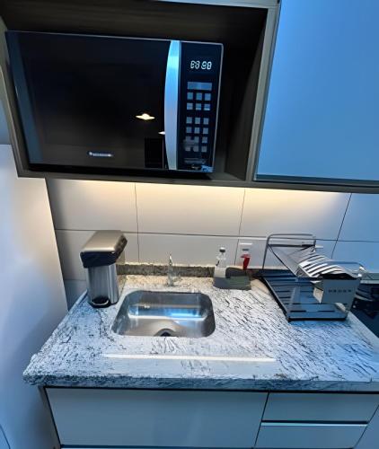 a kitchen counter with a sink with a microwave at Valente Prime Loft – Executive apartment in Extrema, MG in Extrema
