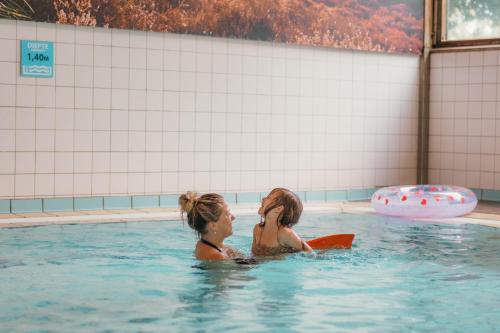 two women are sitting in a swimming pool at Salland Duo Bungalows in Nieuw-Heeten