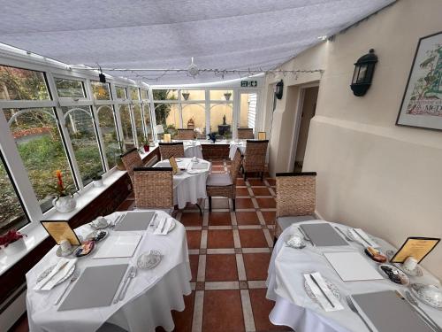a restaurant with white tables and chairs and windows at The Beaumont in Sittingbourne