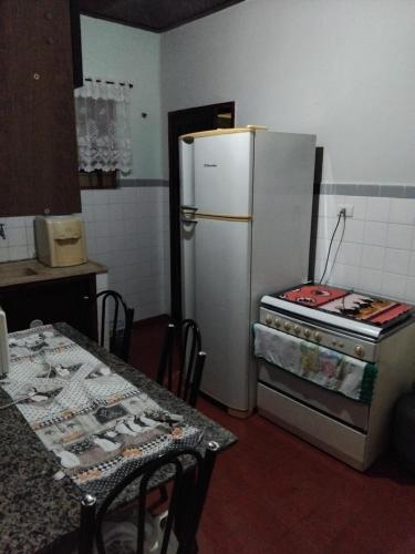 une cuisine avec un réfrigérateur et un four, ainsi qu'une table dans l'établissement Casa de praia, à Itanhaém